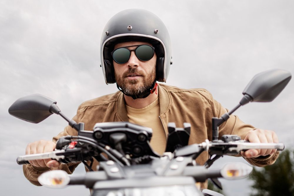 Handsome bearded brutal biker wearing helmet and stylish sunglasses